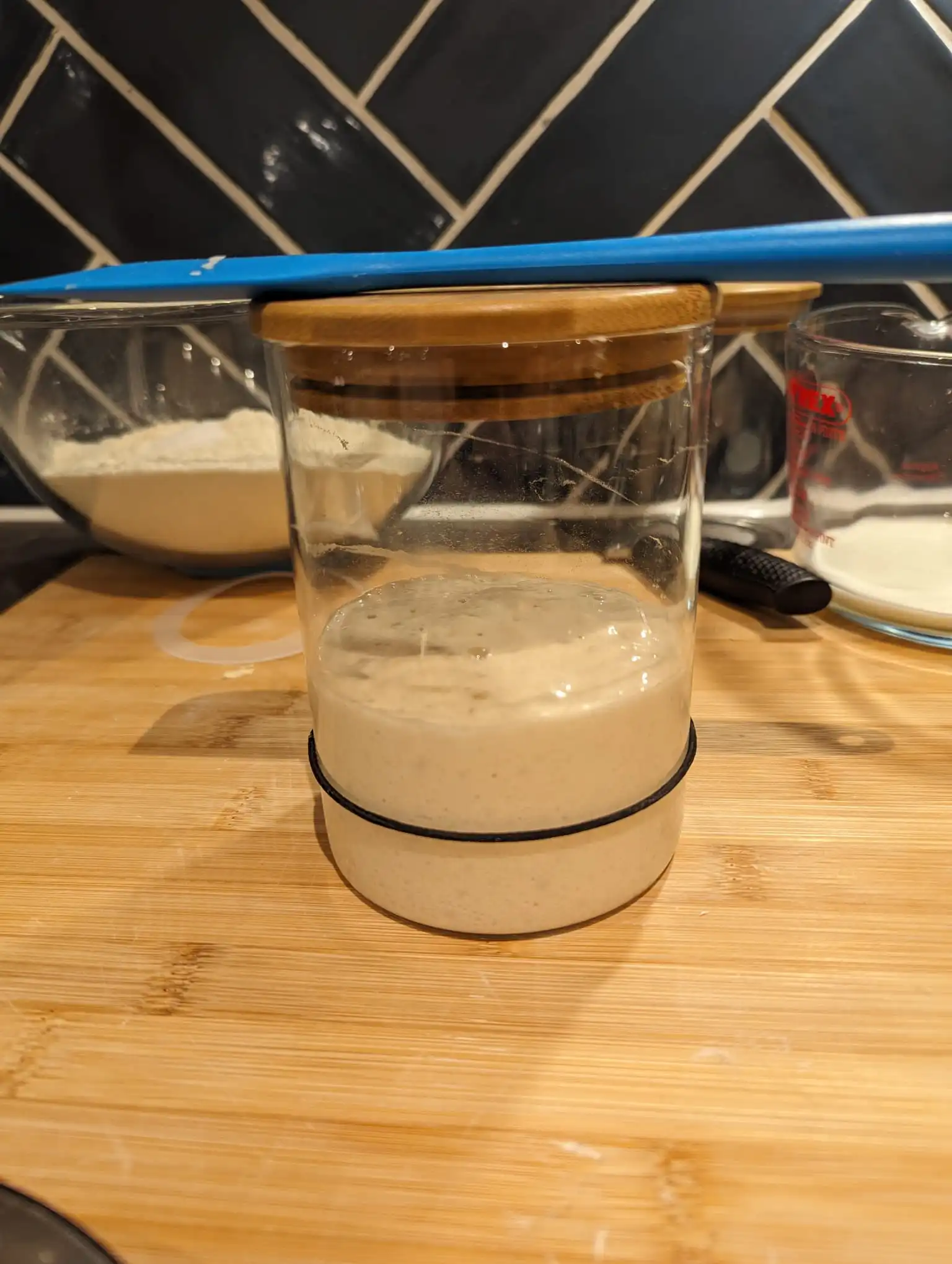 Jarred sourdough starter with silicone spatula resting on top